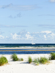 Vertical shot of a white beach with a boat sailing on the sea in Bornholm, Germany