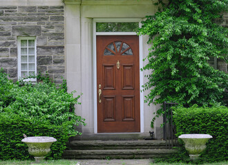 Fototapeta na wymiar wood grain front door of old stone house with shrubbery