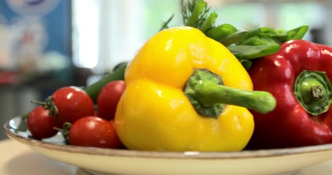 Video of freshly washed vegetables and greens: tomatoes, sweet pepper, green onions and dill spinning on a round white plate. Rotating vegetables.