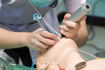 Anesthesiologist performing an orotracheal intubation on a simulation, Medical manipulation. mannequin dummy during medical training to control of the airway. - Powered by Adobe