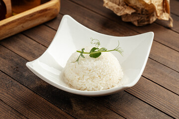 Plate of boiled white rice garnish portion on a wooden background