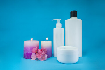 Close up template of spa cosmetic products on blue background, with candles. Minimal concept. Showcase for presentation skincare products