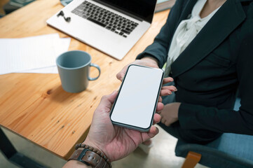 Closeup image of man hand passing mobile with blank screen to his partnership while working in office.