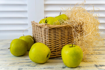 Green apples and basket with apples on wooden background