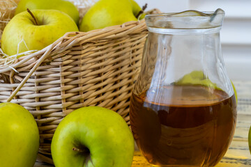 Green apples, basket with apples and jug with apple juice on wooden background