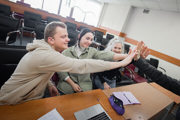 Students and lecturer give a high five in the university classroom.