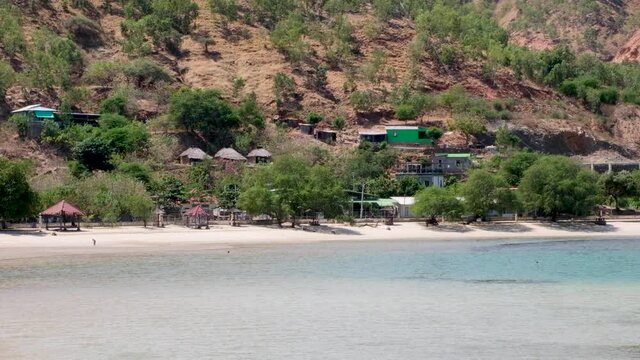 Traditional Timorese Houses In The Hills And Children Playing In The Sea On Stunning White Sand Beach Tropical Island Coastline In Dili, Timor Leste, Southeast Asia