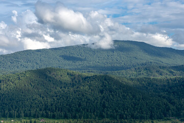 white fluffy clouds on blue sky and mountain peaks