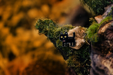 black cat toy close up in forest, autumn natural background. black cat - symbol of witchcraft, Halloween holiday. fall season