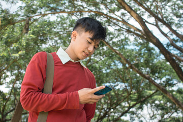 A young male worker watches online videos or checks his social media while taking a walk to work....