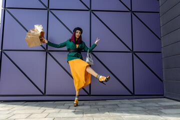A happy shopaholic girl throws her bags near a shopping center. Have fun shopping on Black Friday. the girl in the store is happy with her purchases, throws packages. Consumer concept.