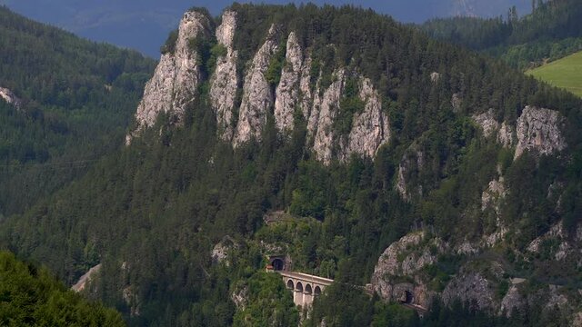 Slow tilt up over rocky cliffs with train tracks in stunning nature landscape
