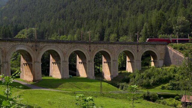 Slow pan over viaduct bridge at Semmering Railway with train running through it