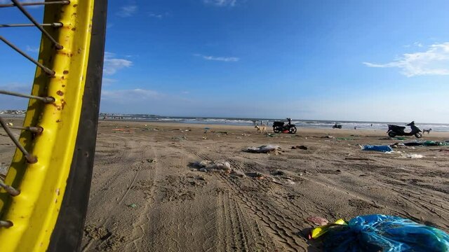 POV Next To Wheel As Scooter Rides Onto Beach Heavily Polluted With Trash