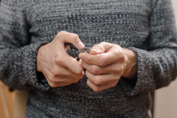 Closeup of young guy cutting his fingernails with nail clipper, time for yourself men