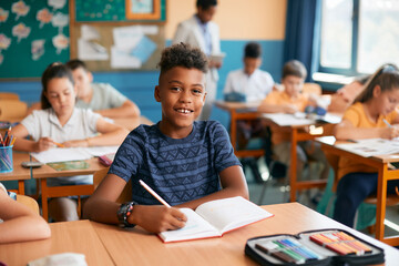 Happy African American schoolboy during class at elementary school. - obrazy, fototapety, plakaty