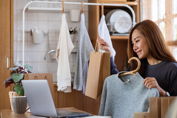 A female entrepreneur using laptop computer for selling clothes online or review product on social media at home