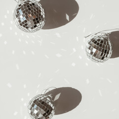 Small shining disco balls with sparkling glitter sunlight shadows on white background. Minimal...