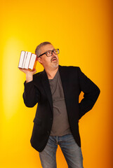 Portrait of smart responsible man with modern hairstyle looking sideways at place for text on yellow isolated background, holding book in hands Executives employment concept