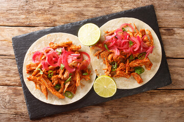 Yucatan Braised Pulled Pork Cochinita Pibil with tortilla and marinated onion closeup in the slate...