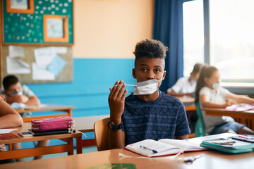 African American student wears face mask at elementary school due to COVID-19 pandemic.