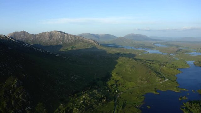 Twelve Bens Mountains, Recess, Connemara, County Galway, Ireland, July 2021. Drone slowly tracks west over Ballynahinch Lake, while facing east towards Ballinafad and Maam.
