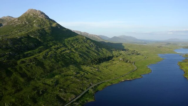 Twelve Bens Mountains, Recess, Connemara, County Galway, Ireland, July 2021. Drone slowly pushes east over Ballynahinch Lake and Garraun mountain complex with Ballinafad and Maam in the distance.