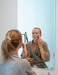 Woman applying face mask in the bathroom