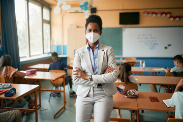 Black teacher wears protective face mask while teaching students at elementary school during COVID-19 pandemic.