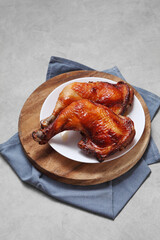 Grilled chicken leg in ceramic dish on wooden tray