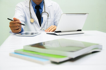 medicine doctor working with computer notebook and digital tablet  at desk in the hospital