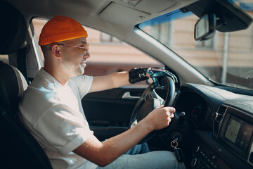 Young disabled man driver with artificial prosthetic hand driving riding vehicle car. Hands on...