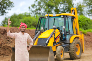 Indian farmer standing with his new earth mover machinery.