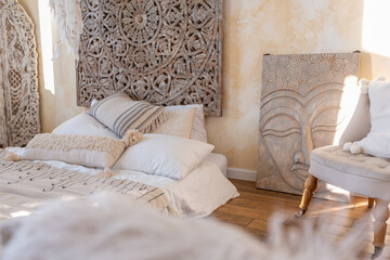 modern interior of a bright room in a two-storey apartment with decorative items in bali style with a balcony. white walls, wood floors and vintage furniture