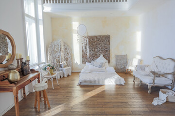 modern interior of a bright room in a two-storey apartment with decorative items in bali style with a balcony. white walls, wood floors and vintage furniture