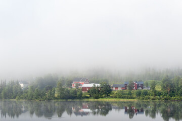 Fototapeta na wymiar Village at a mirrored lake in the woodland