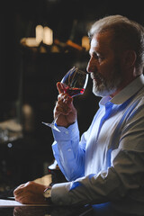 A senior sommelier is tasting red wine.