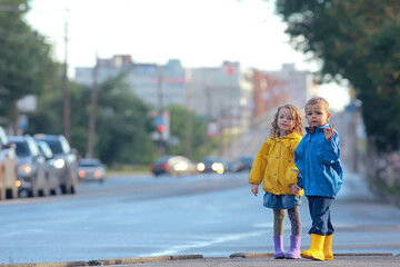children brother and sister play autumn rain / October weather little children walk in the city