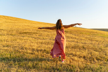 libertà è una donna che corre a braccia aperte in un campo di grano in toscana
