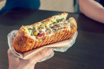 Close-up of hand with fajitas filling with lettuce salad, bacon, tomato, sauces, cheese and vegetables.