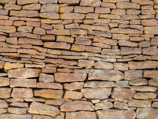 The fence is made of different stones.