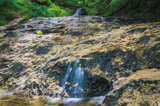 Small waterfall on large stone in Austrian Alps, klausbach river, valley near attersee. Long exposure