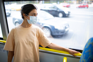 Indian Woman ride in public transport bus window or tram in medical face mask - Powered by Adobe