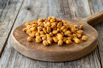 Roasted corn snack. Corn nuts with sauce on wood background. bulk corn nut grains