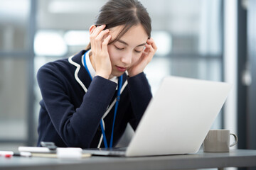 仕事中、頭痛に悩む女性