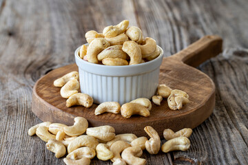 Roasted Cashews. Cashew nuts on wood background. Bulk Cashews. Cashew on ceramic plate