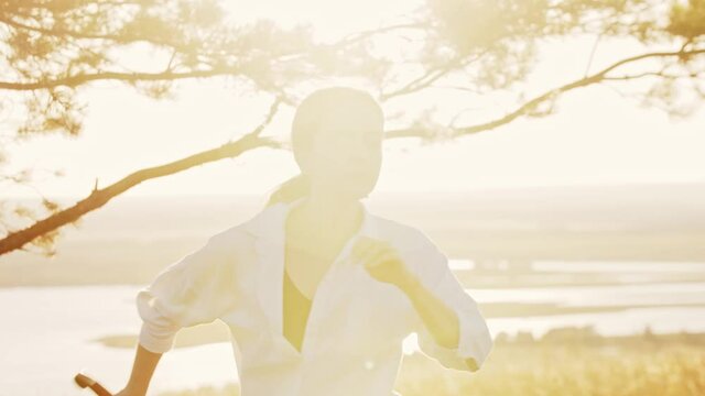 Young woman in a white shirt doing swordplay on nature