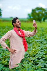 Indian farmer using smartphone at agriculture field.