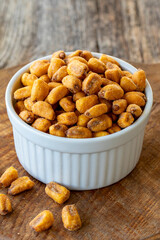Roasted corn snack. Corn nuts with sauce on wood background. Bulk corn nut grains. Roasted corn nuts on a ceramic plate