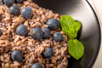 Delicious risotto with blueberries served on white wooden table